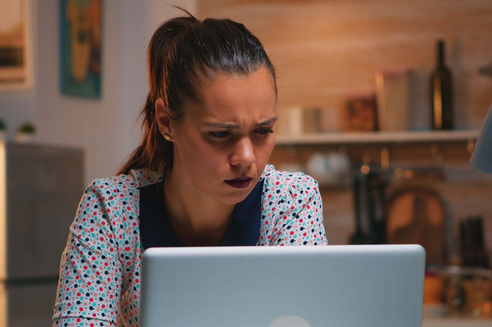 A woman squinting while looking at a laptop
