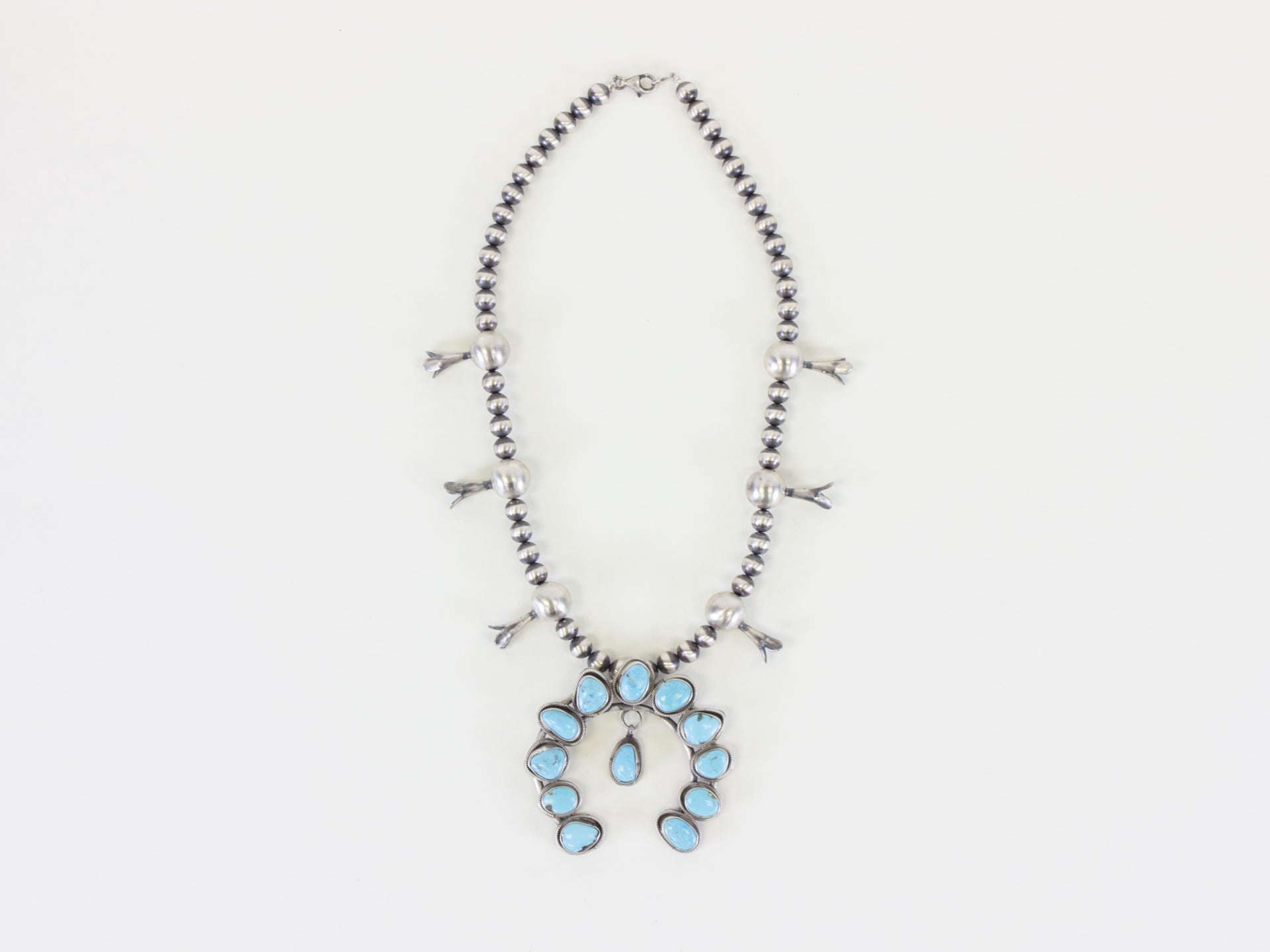 A sterling silver squash blossom necklace featuring Kingman turquoise, crafted by Navajo silversmith Harrison Yazzie, purchased and provided by El Palacio Magazine and the Museum of Indian Arts & Culture.