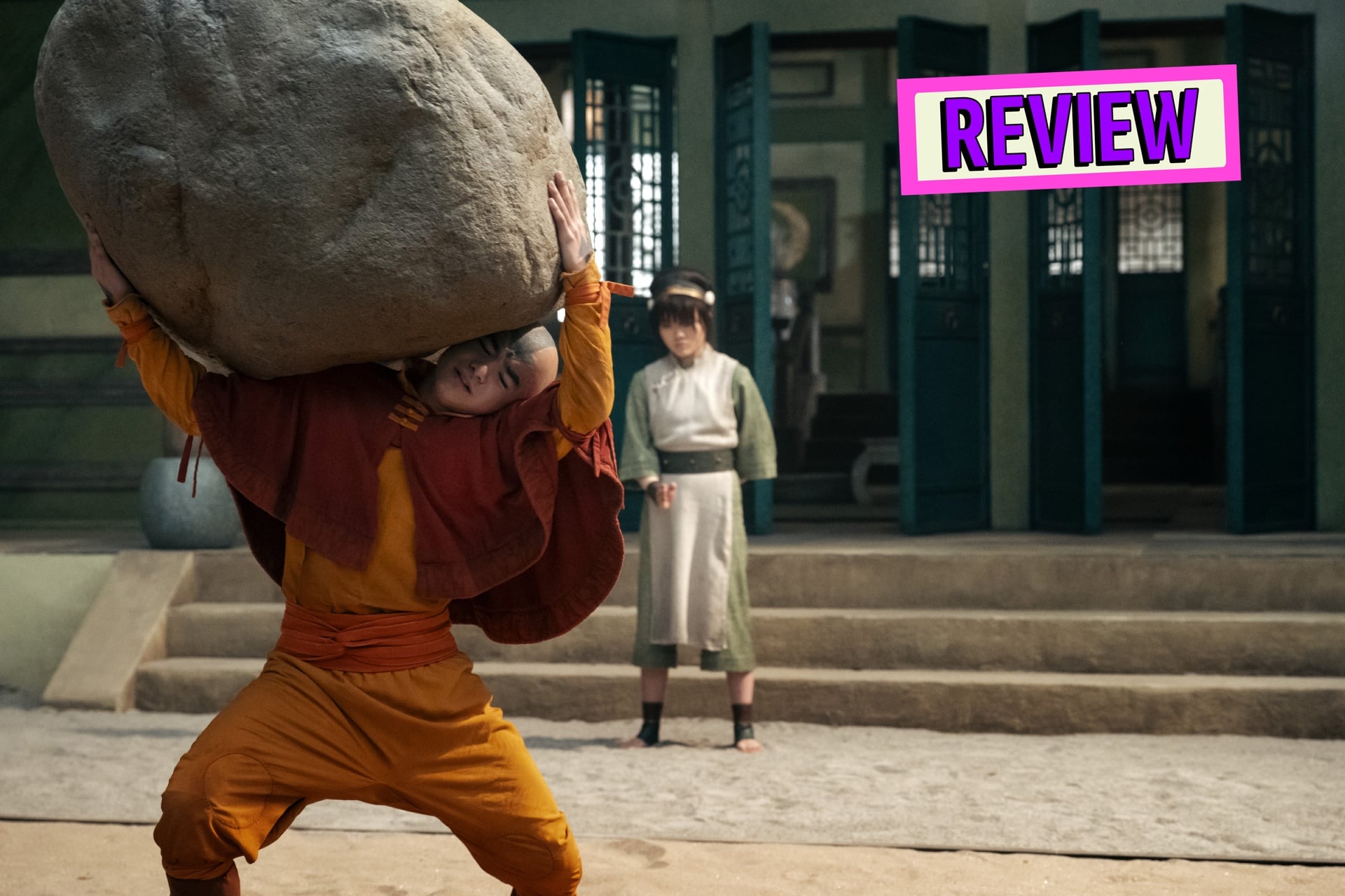 Avatar: The Last Airbender image of Aang carrying a boulder while Toph watches on.