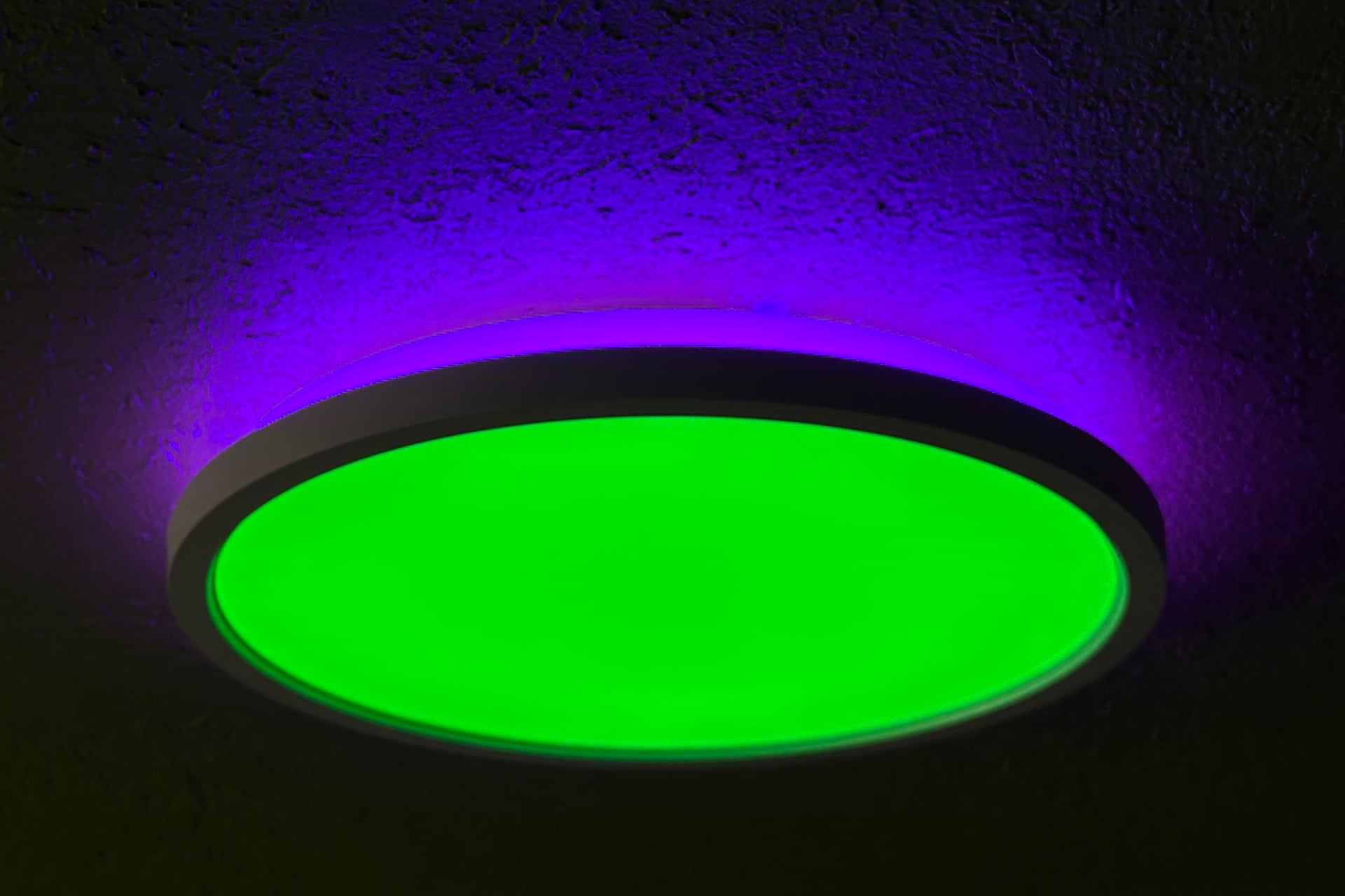 Nanoleaf Smart Multicolor Ceiling Light showing green on the bottom and purple on its top light.