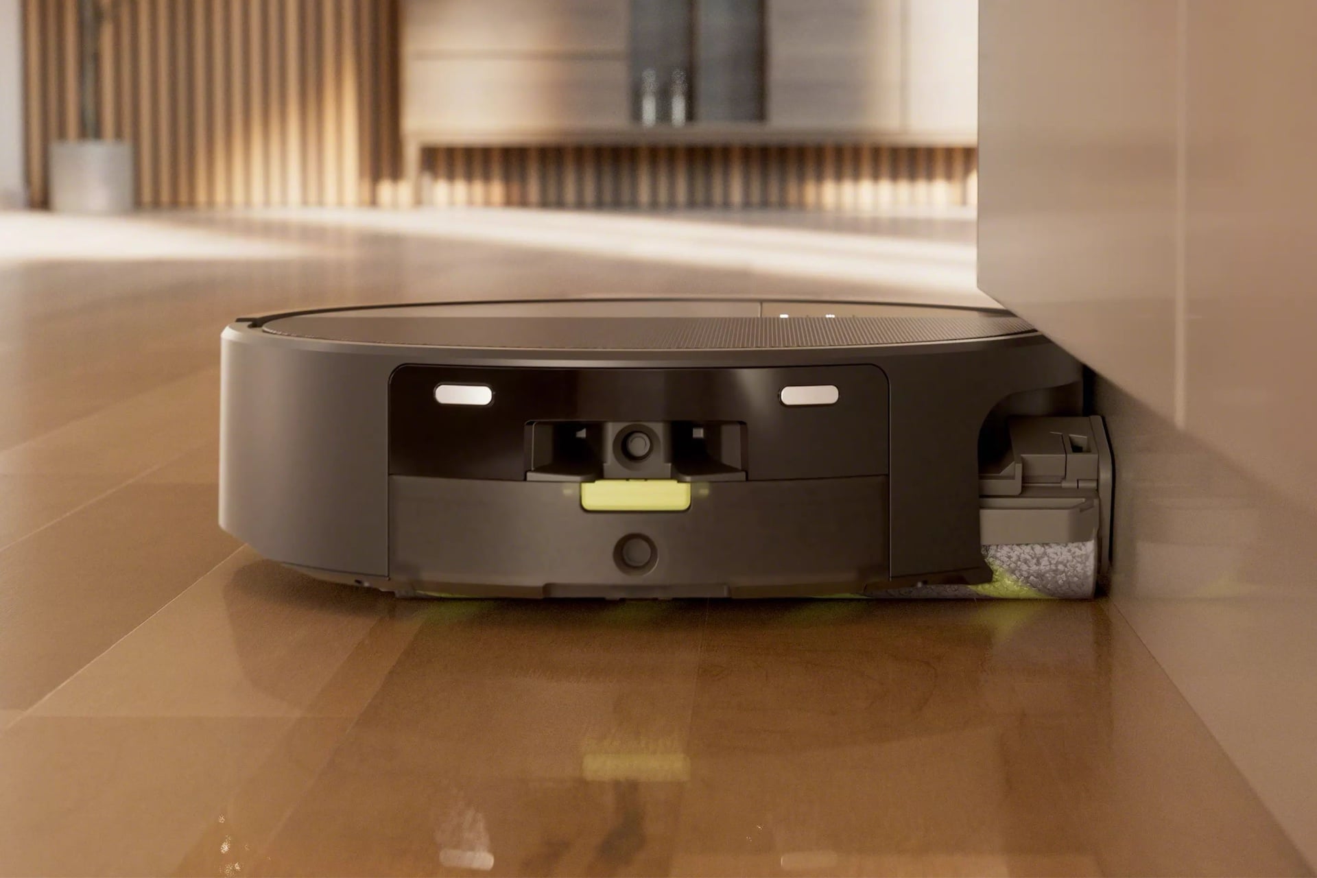 Picture of the Roomba Max 775 from the rear, with its mop roller appearing to extend out to get close to the edge of a wall.