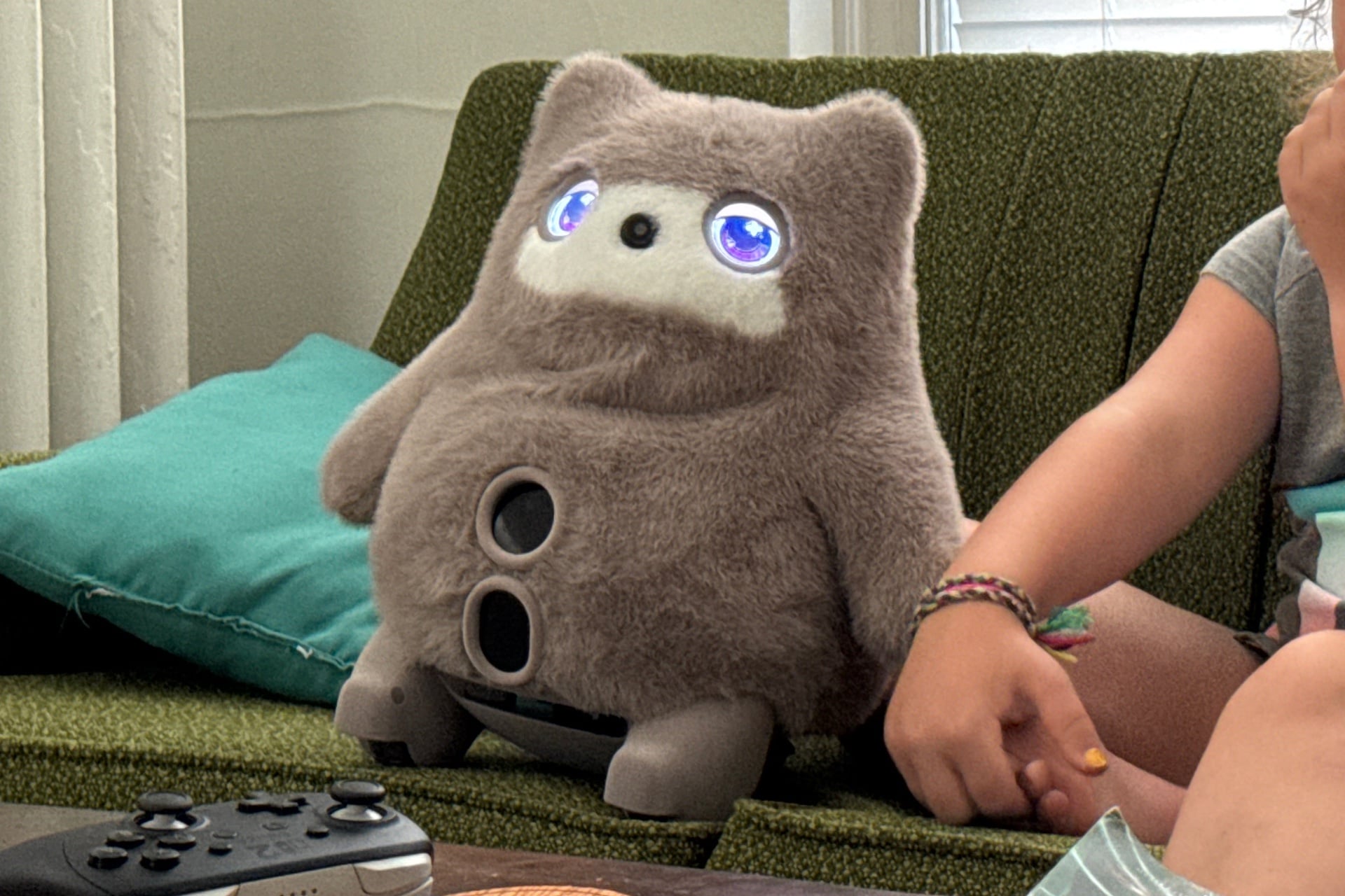 Switchbot Kata Friends perched on a green couch, next to a child