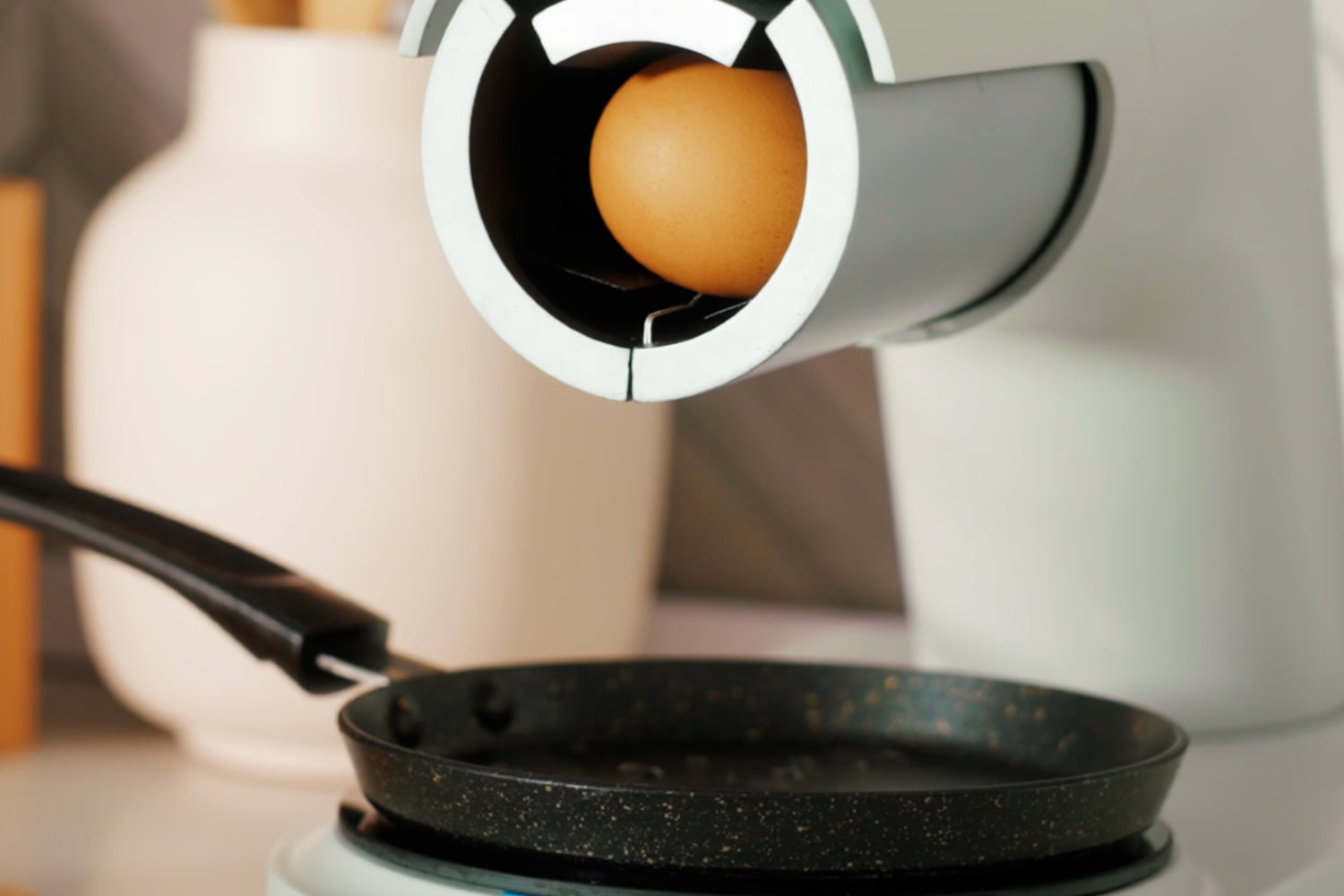 Cheffy egg robot shown holding egg over pan