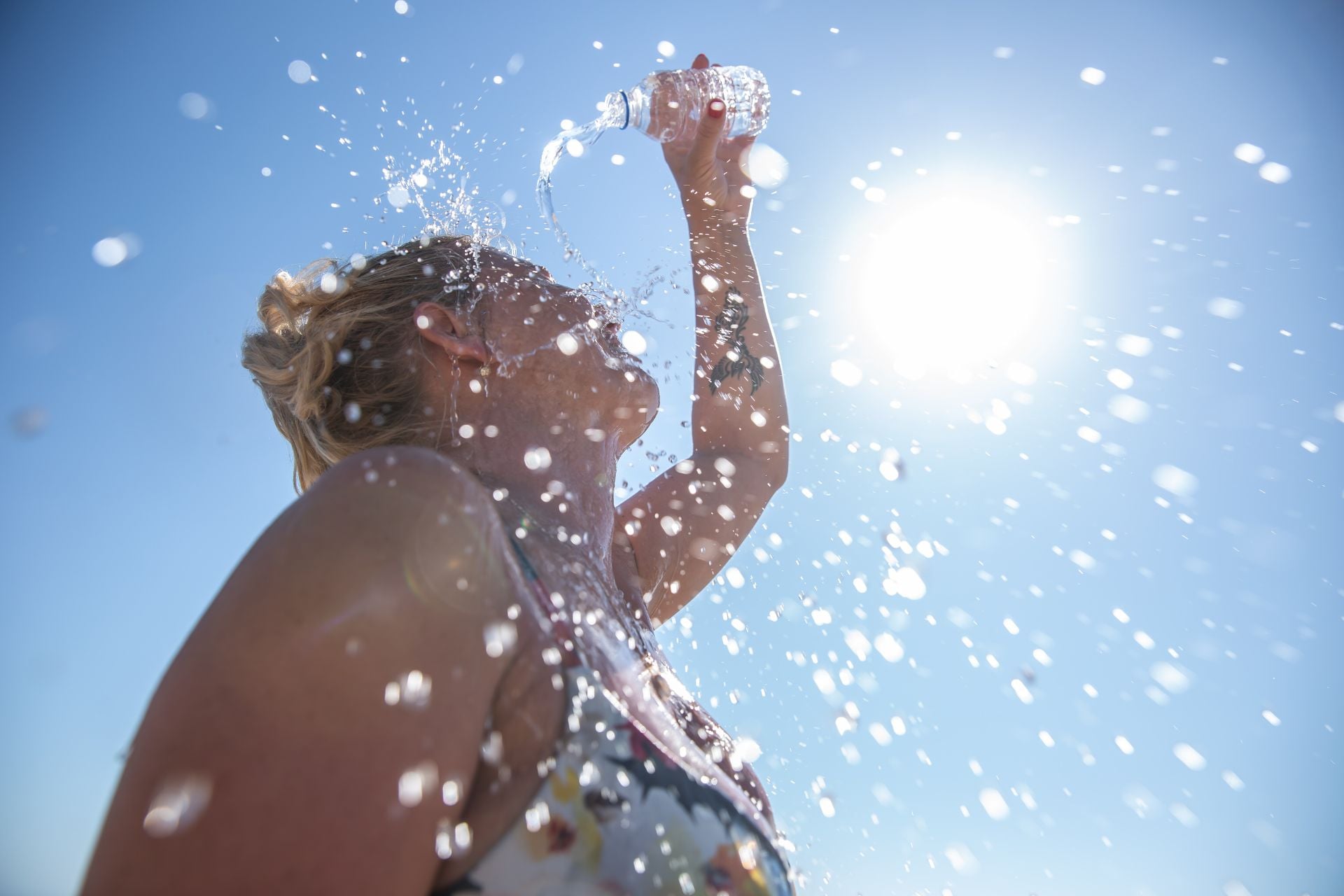 A woman dumps bottled water on her head to beat the summer heat.