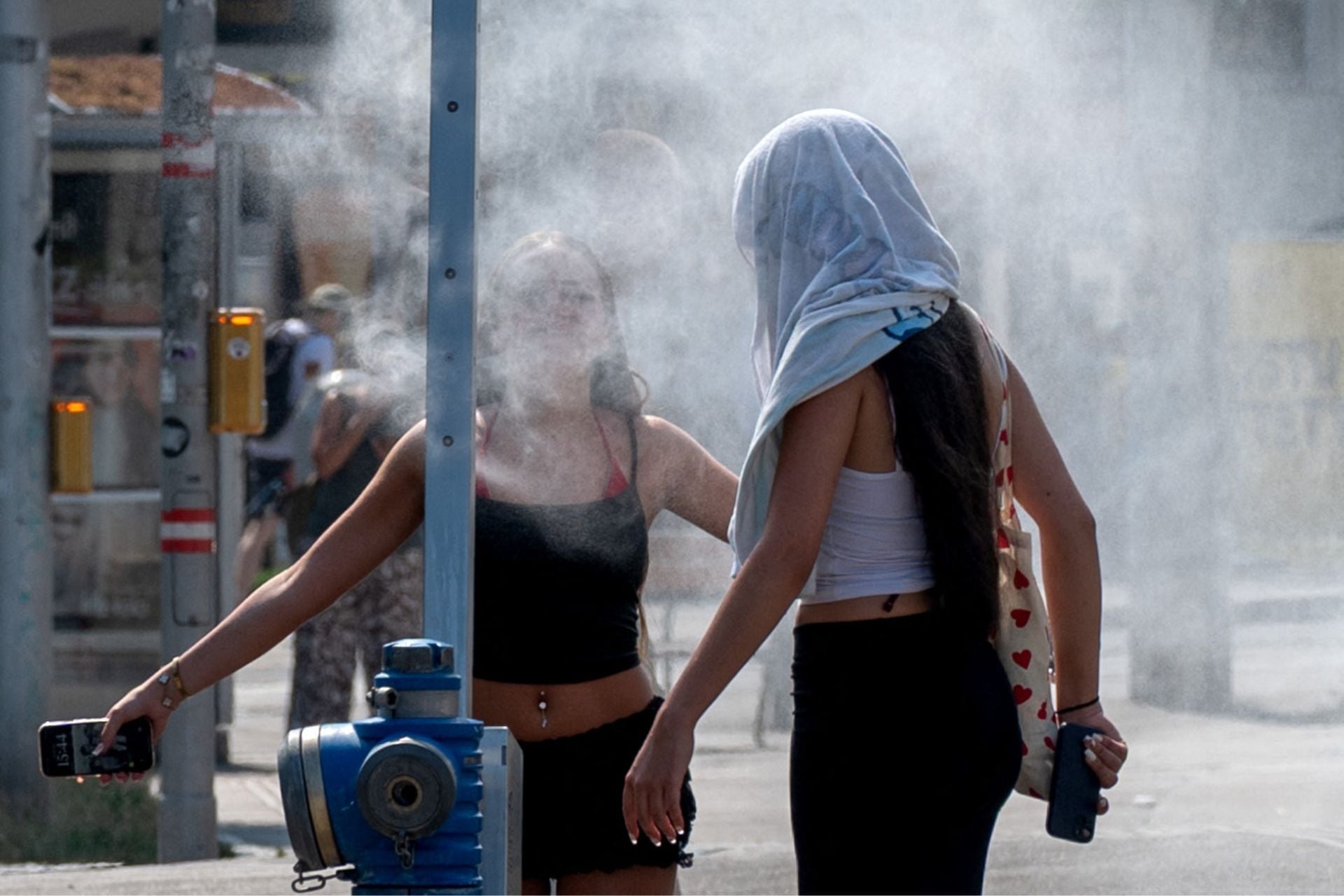 Women cool down in a water sprayer as a brutal heatwave persists in Vienna, Austria, on June 30, 2026. 