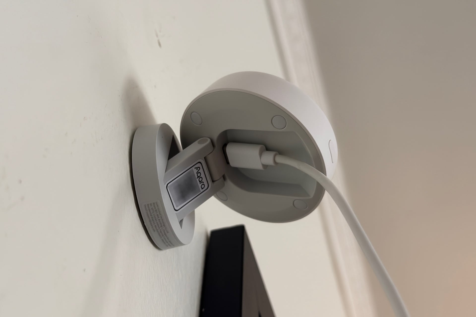 Aqara Fp400 pictured at partial extension with the main body tilted up, so that the QR code, which has been digitally blurred, and USB-C plug are visible. The USB-C plug and cable rest in a recessed cavity in the back of the main body.