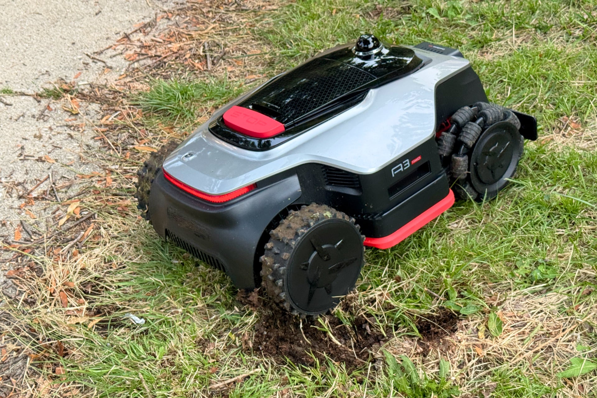 Dreame A3 Awd Pro 3500 just after having dug a rut in the grass, revealing moist dirt beneath.