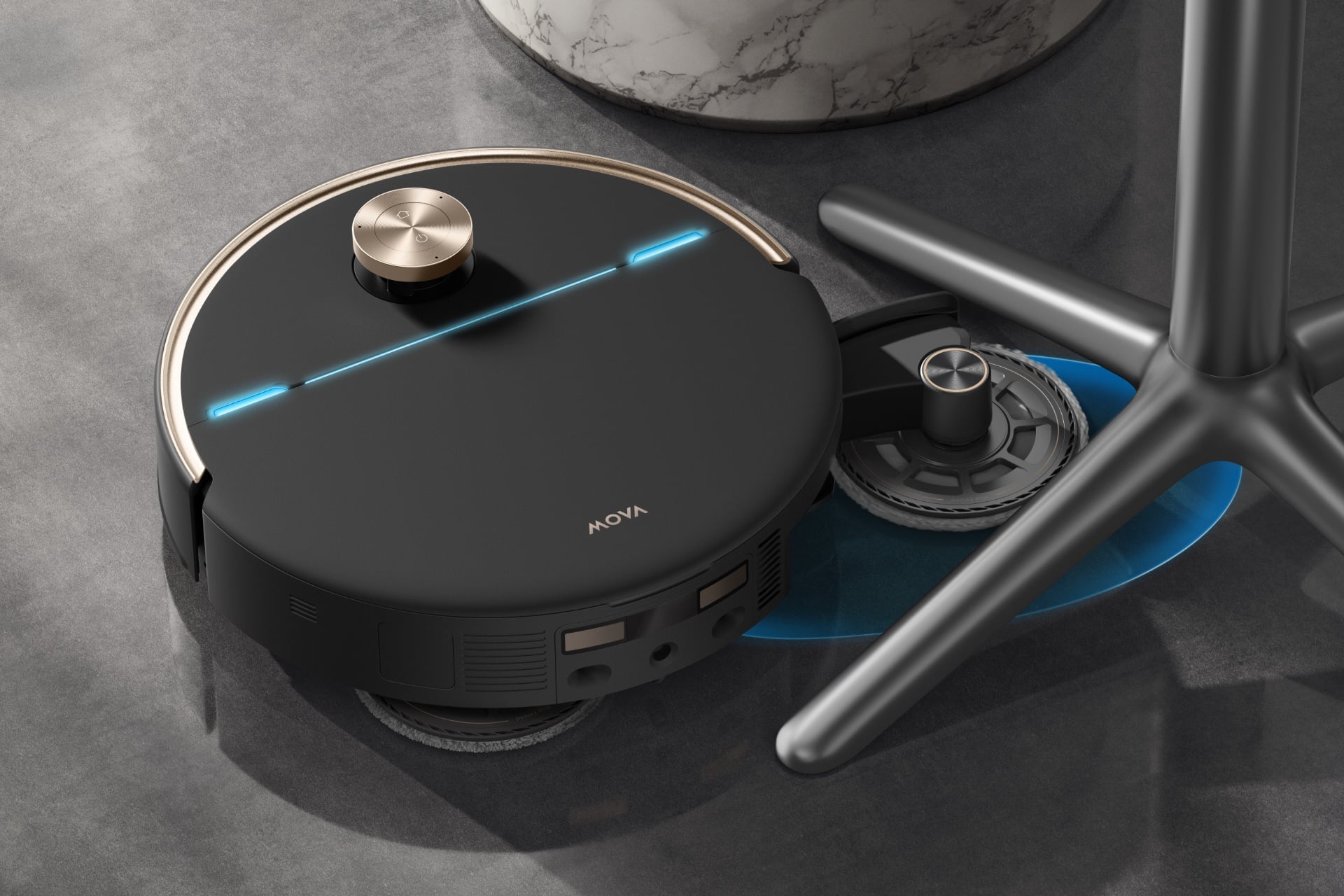 Mova V70 Ultra Complete mopping underneath a chair with a single base that has four splayed-out legs.