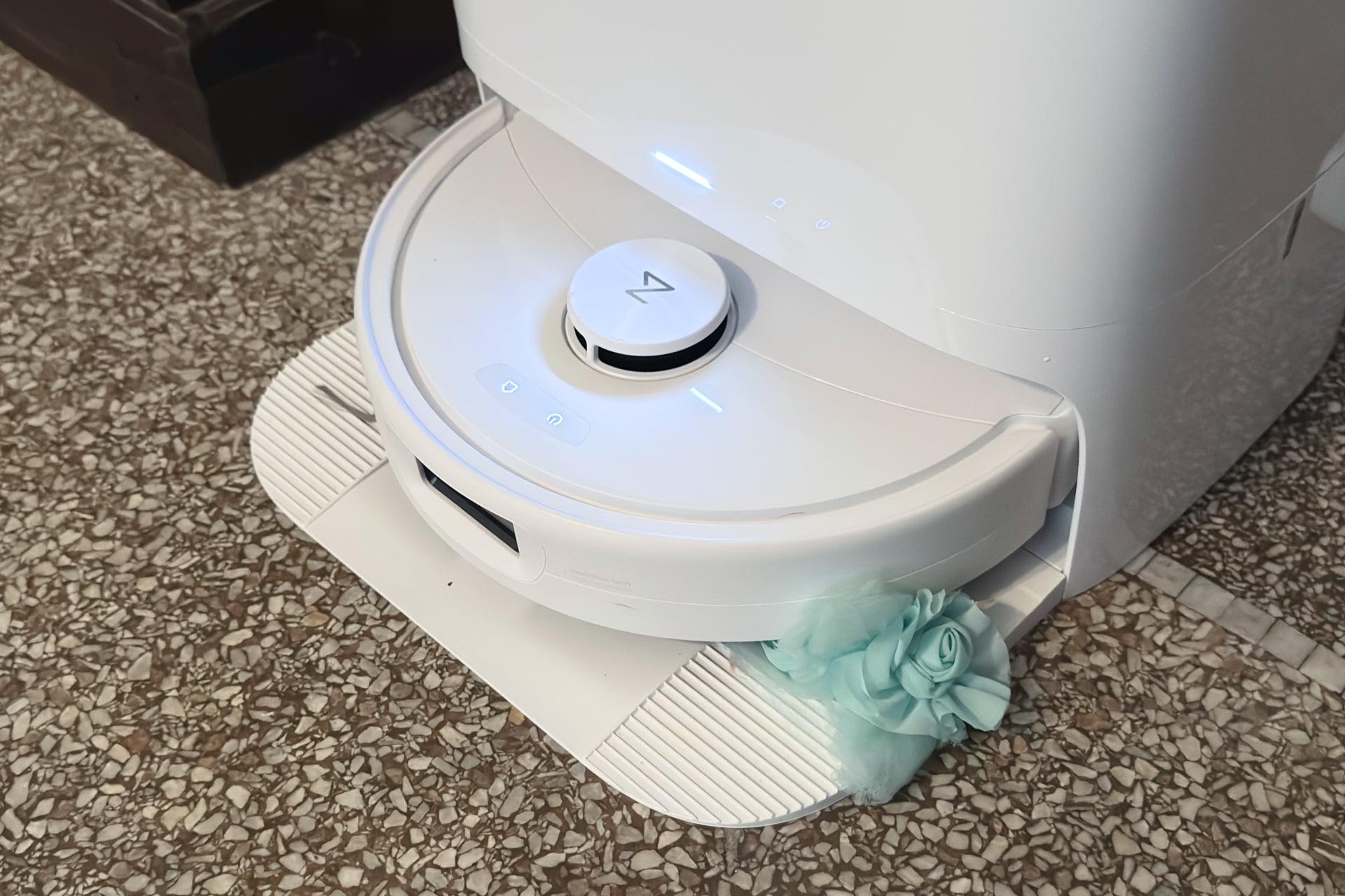 The Roborock Qrevo 2 Pro in its dock with a flowery headband stuck underneath it.