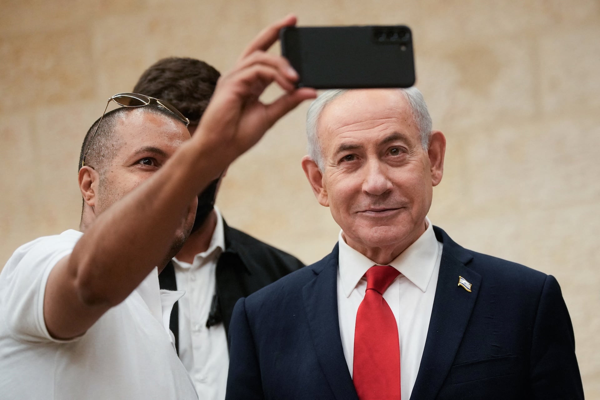 Israeli Prime Minister Benjamin Netanyahu, takes a selfie with a supporter as he arrives to cast his ballot at his party Likud's main polling station during primary elections ahead of Israel's general election in October in Jerusalem on August 17, 2026. 