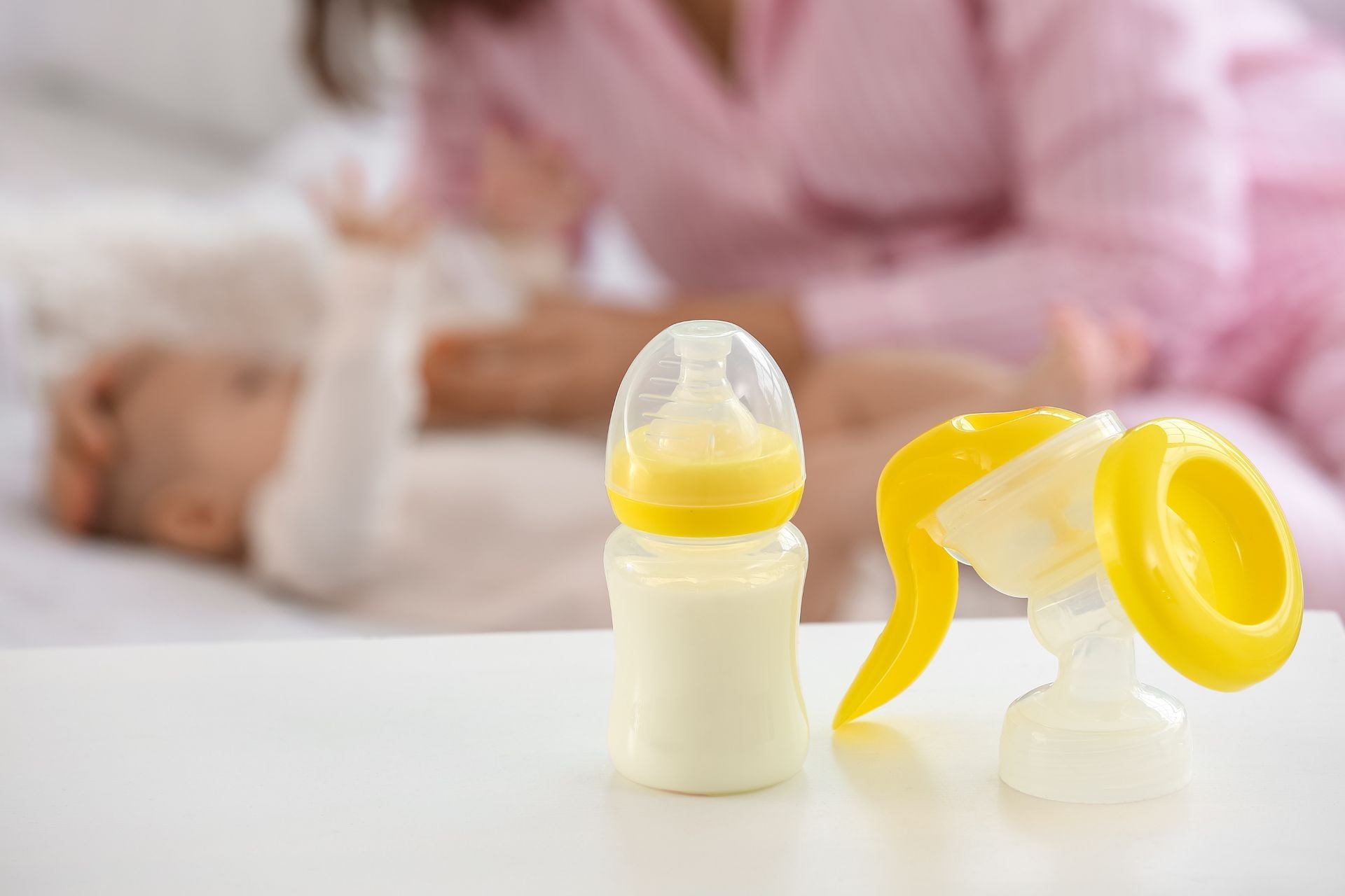 A baby bottle of milk next to a breast milk pump.
