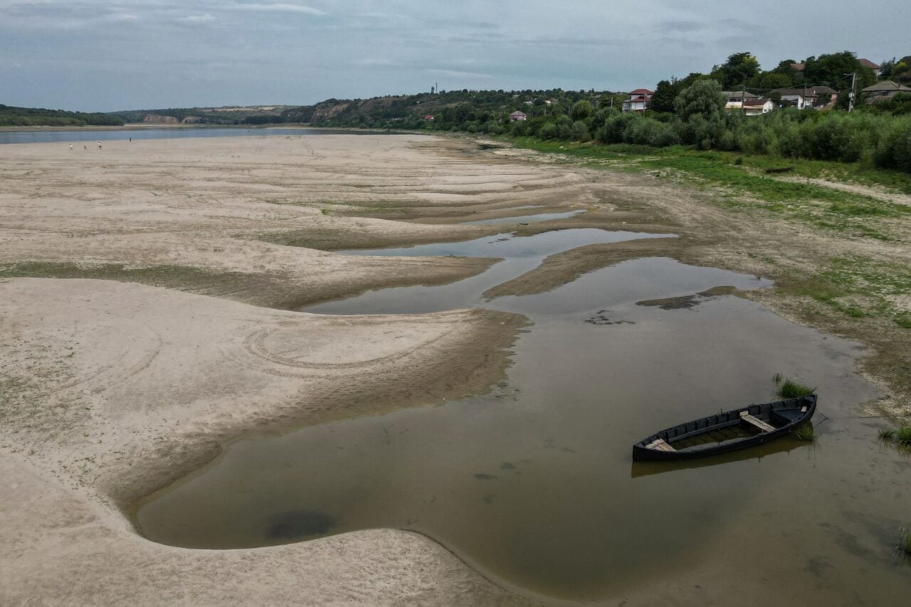 An aerial view of a significantly dried out riverbed with a rowboat in the foreground