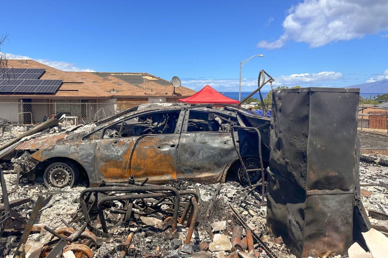 A severely burned car sits amid burned rubble after a major wildfire