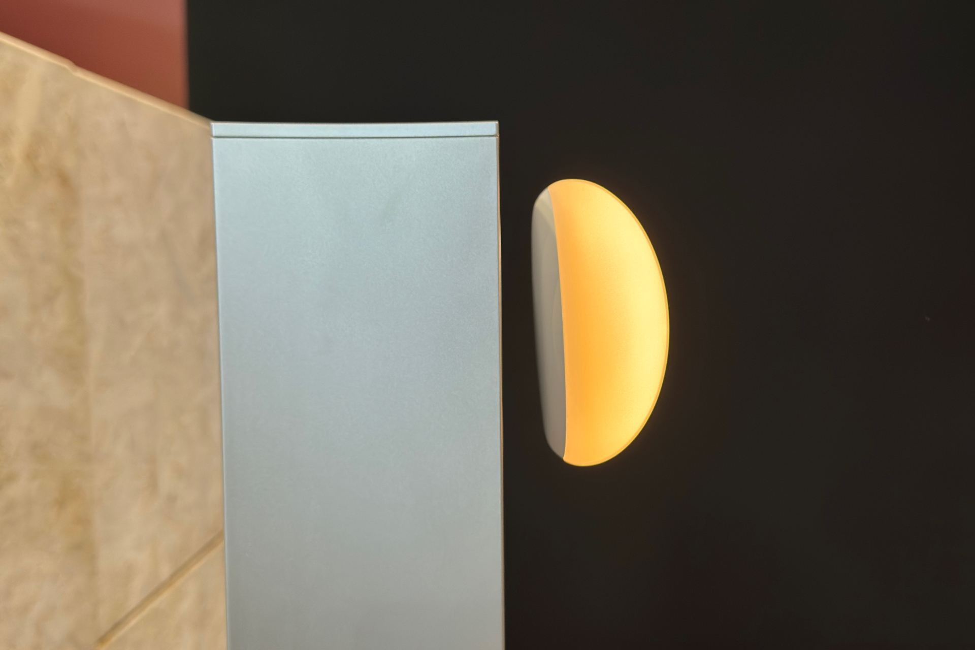 Aura lamp photographed from the side, showing the gap between a square metal post and the rounded light, which is flat on the bottom.