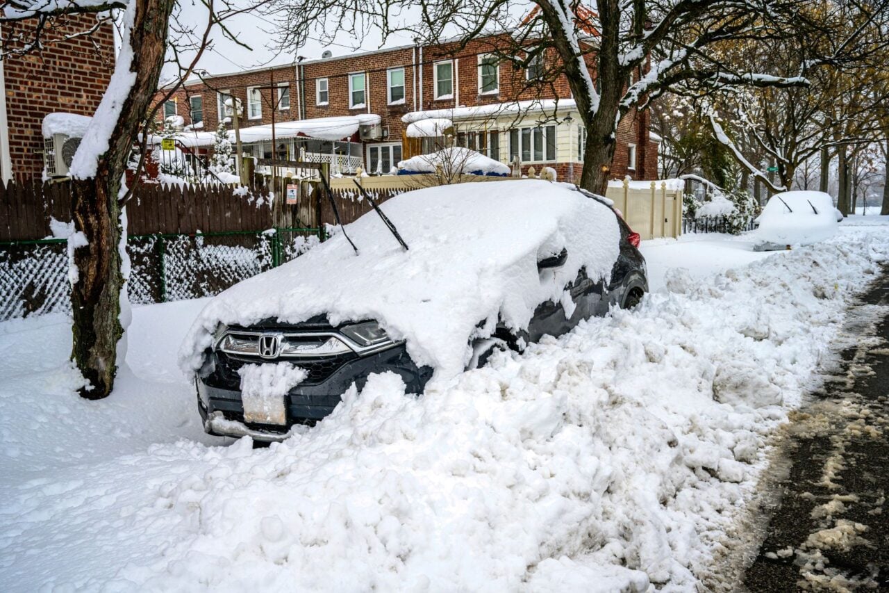 A car buried in snow on the side of the street