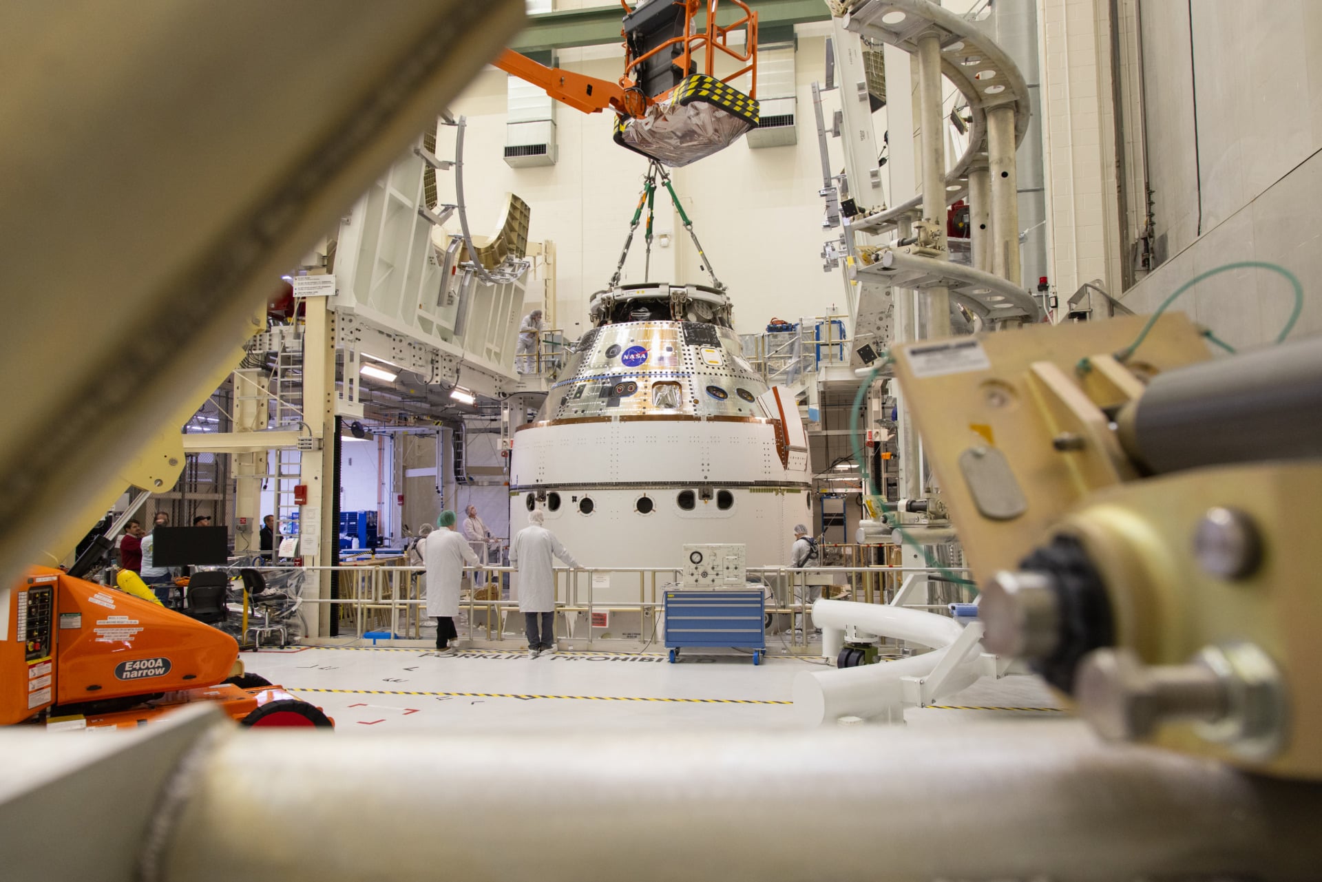 A crane returns NASA’s Artemis II Orion spacecraft to the Final Assembly and System Testing (FAST) cell inside the Neil A. Armstrong Operations and Checkout Building at NASA’s Kennedy Space Center in Florida on Friday, March 21, 2025, following installation of four solar array winds and adapter jettison fairings.