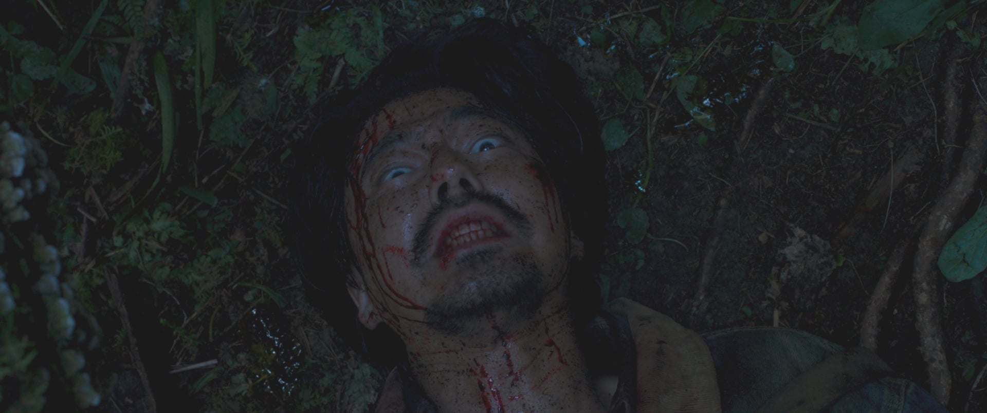Hope still of a bloody hunter looking up at an alien.