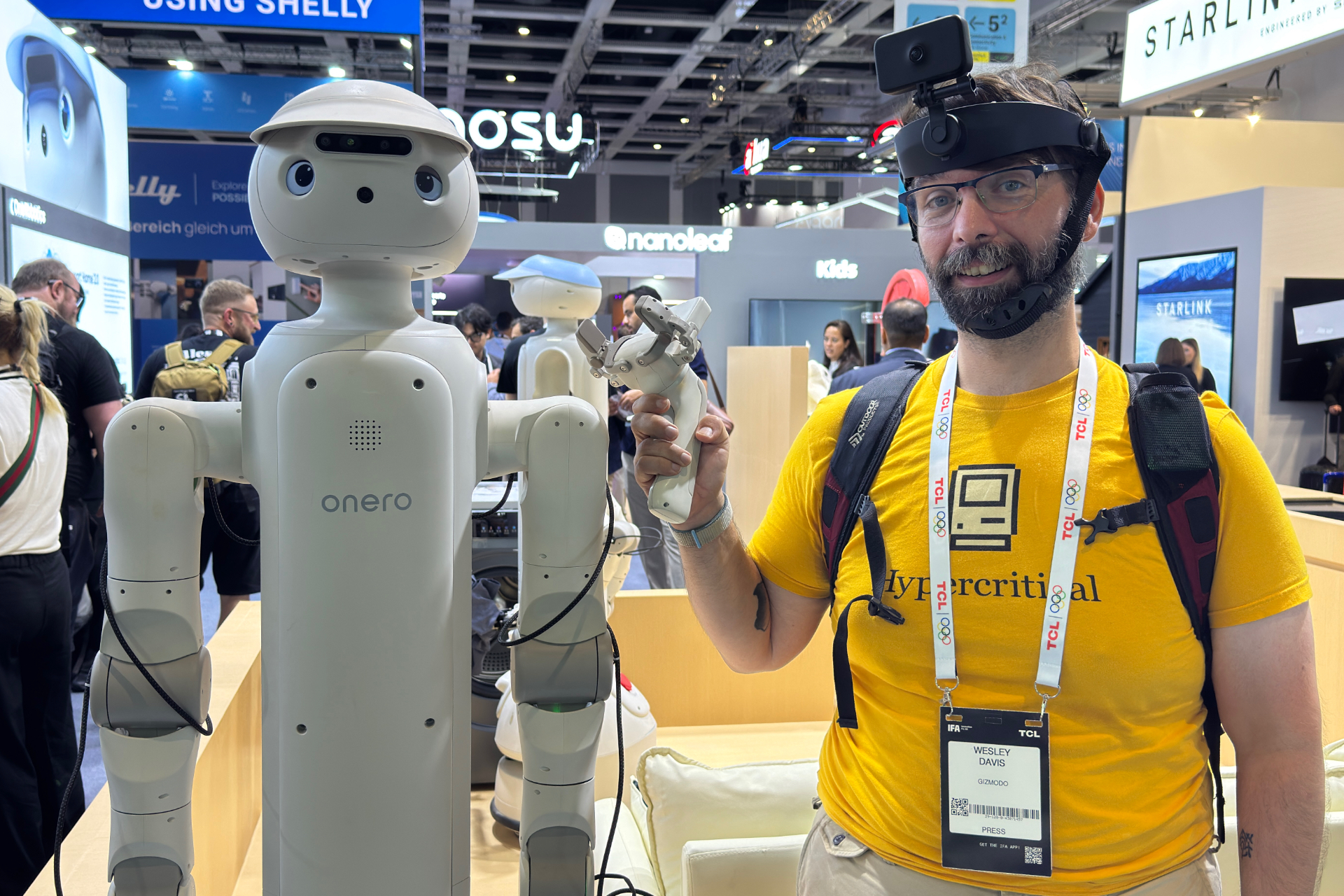 Wes Davis pictured holding the training hands and wearing the headset camera, while standing next to the Onero H1.