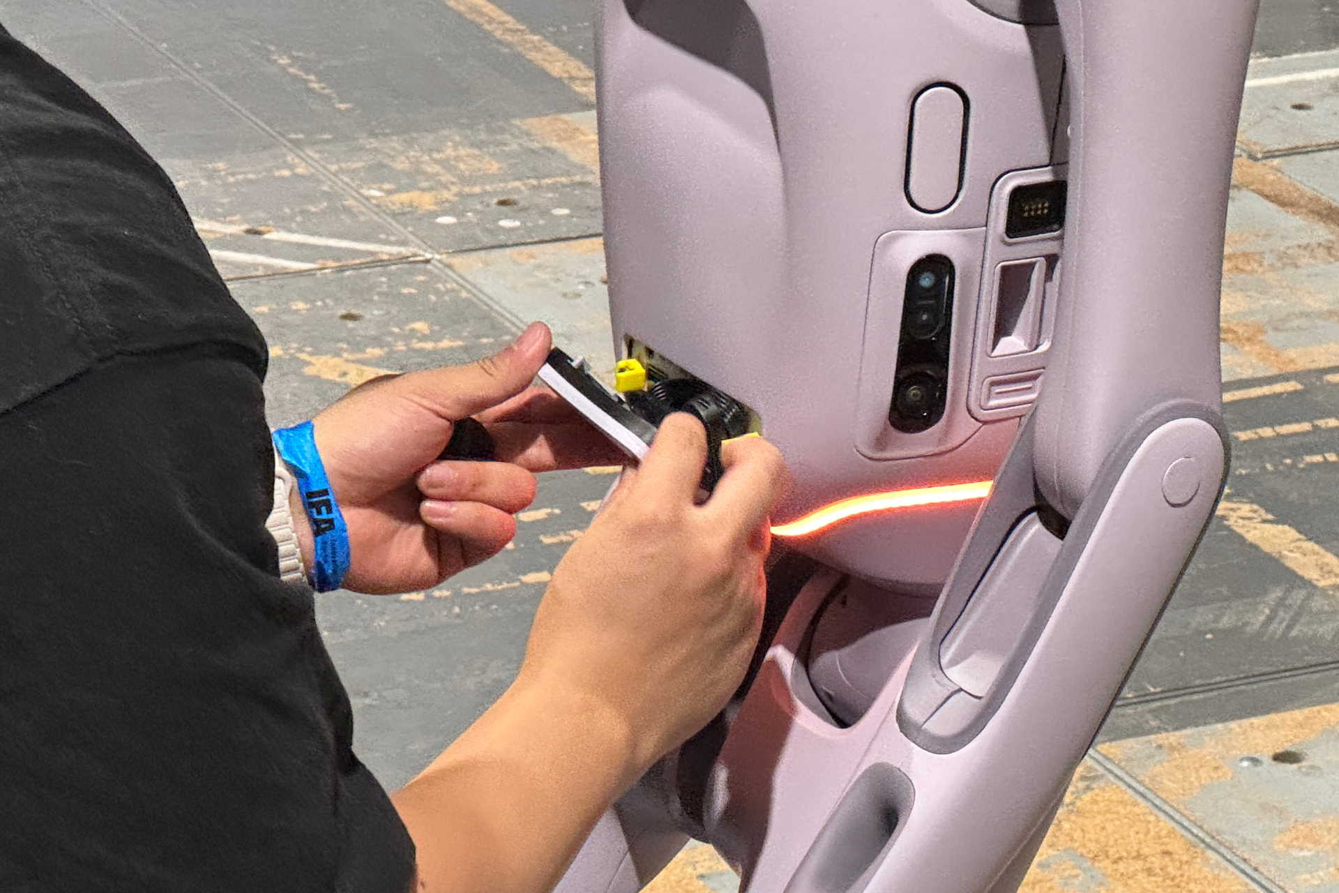 A technician is stuffing the PrimeBot T1's wires back in and closing it up.