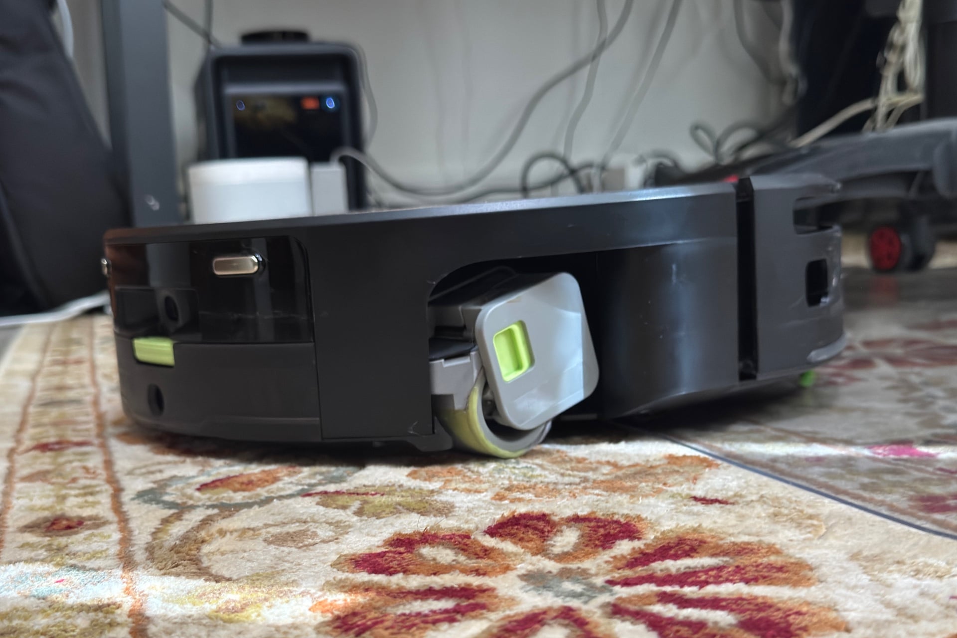 Roomba Max 775 pictured from the side, its mop roller visibly mopping a rug.