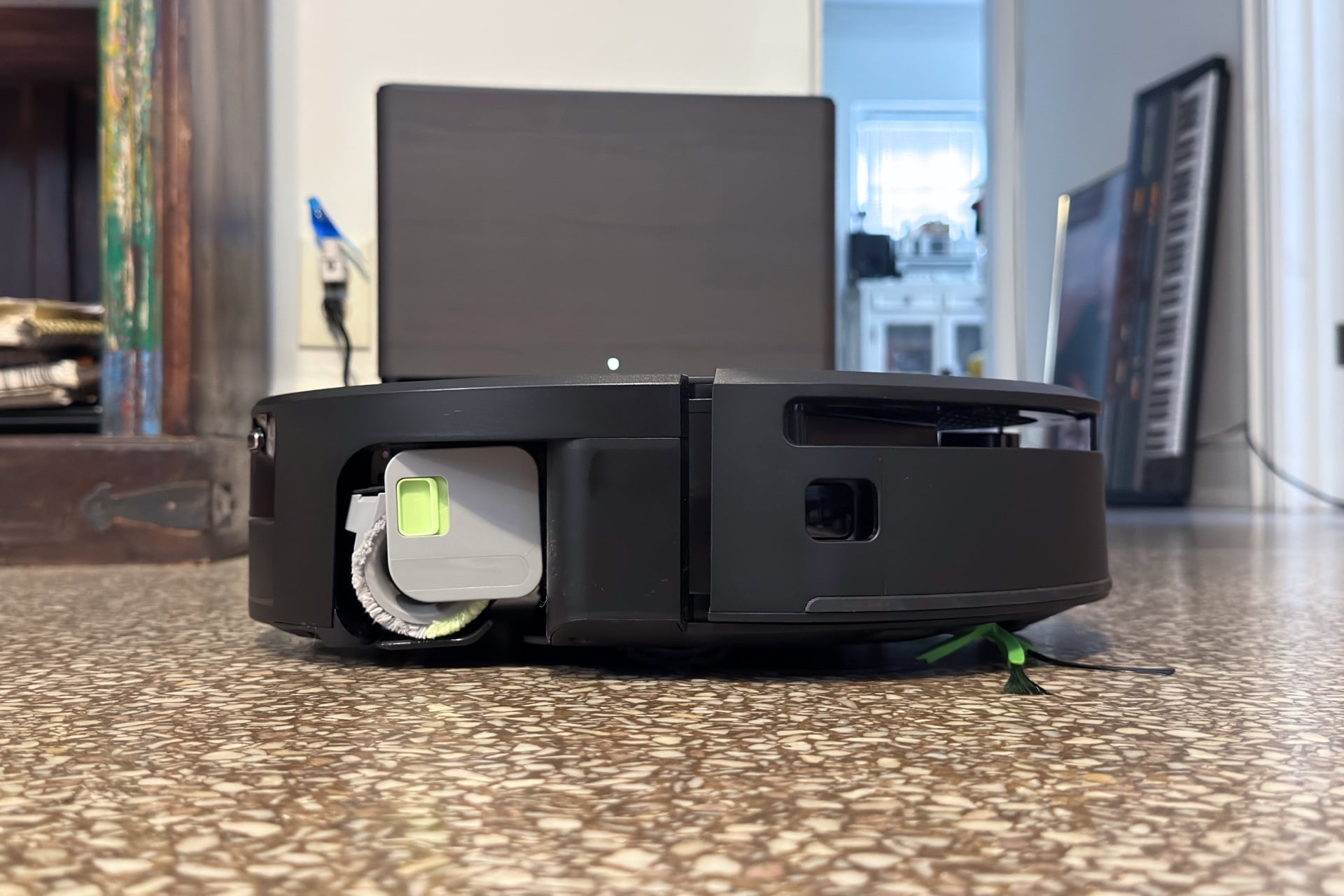 Roomba Max 775 pictured from the side, its mop roller visible, along with the half-LiDAR sensor cutout, which is just below the top panel and goes halfway around the bot.