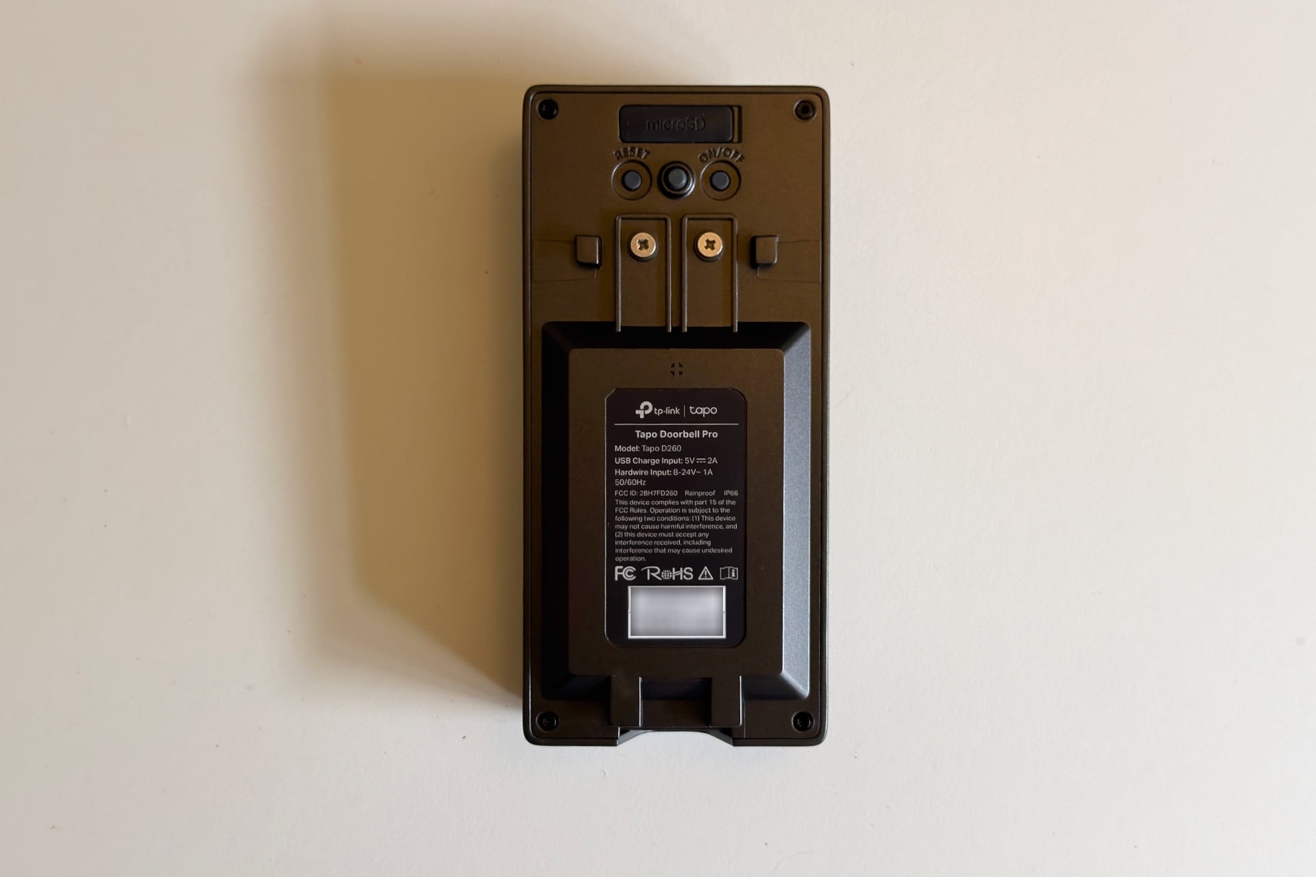 Photo of the back of the Tapo D260, showing its screws for wired connectivity, its microSD port flap cover, and power and reset buttons.
