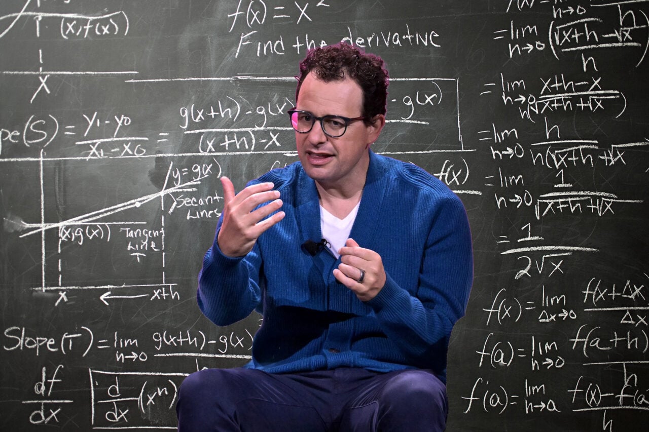 Dario Amodei seen against a chalkboard with math equations