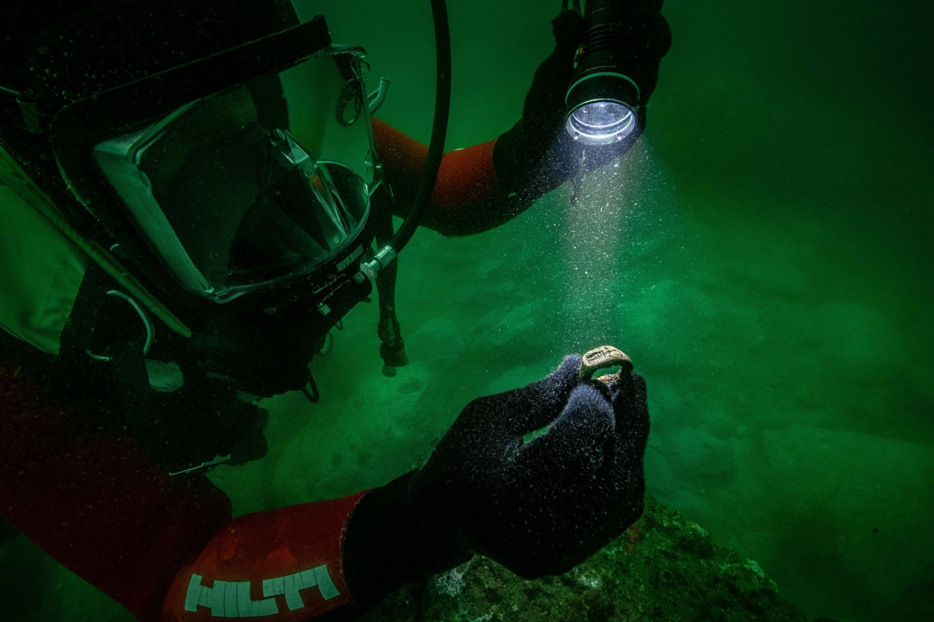 A member of French underwater archaeologist Franck Goddio’s ocean excavation team examines the submerged bronze ring.