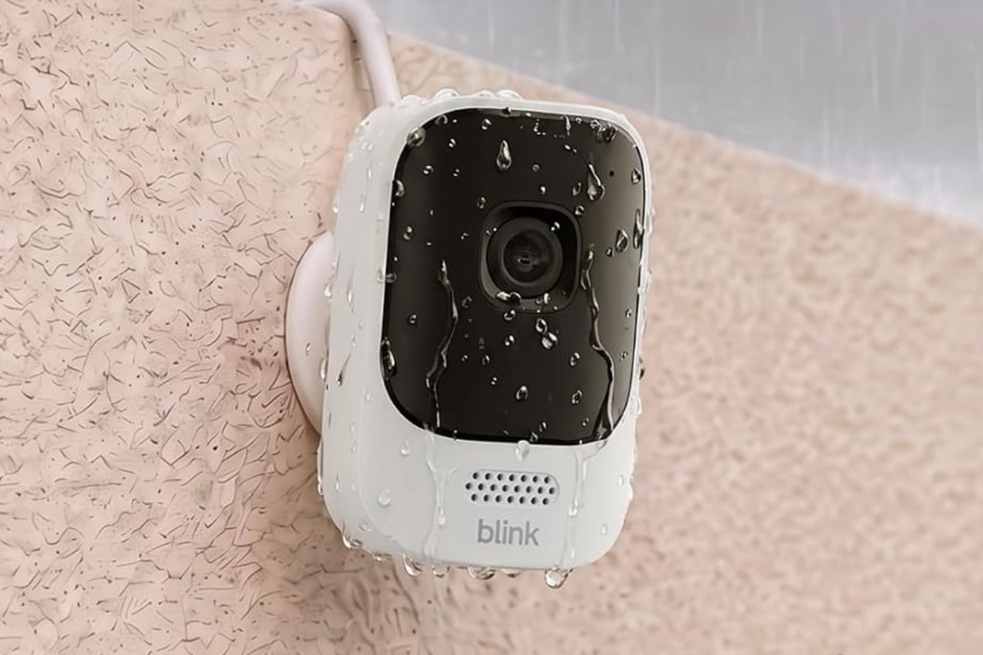 The Blink Mini 4K Plus, covered in water droplets.