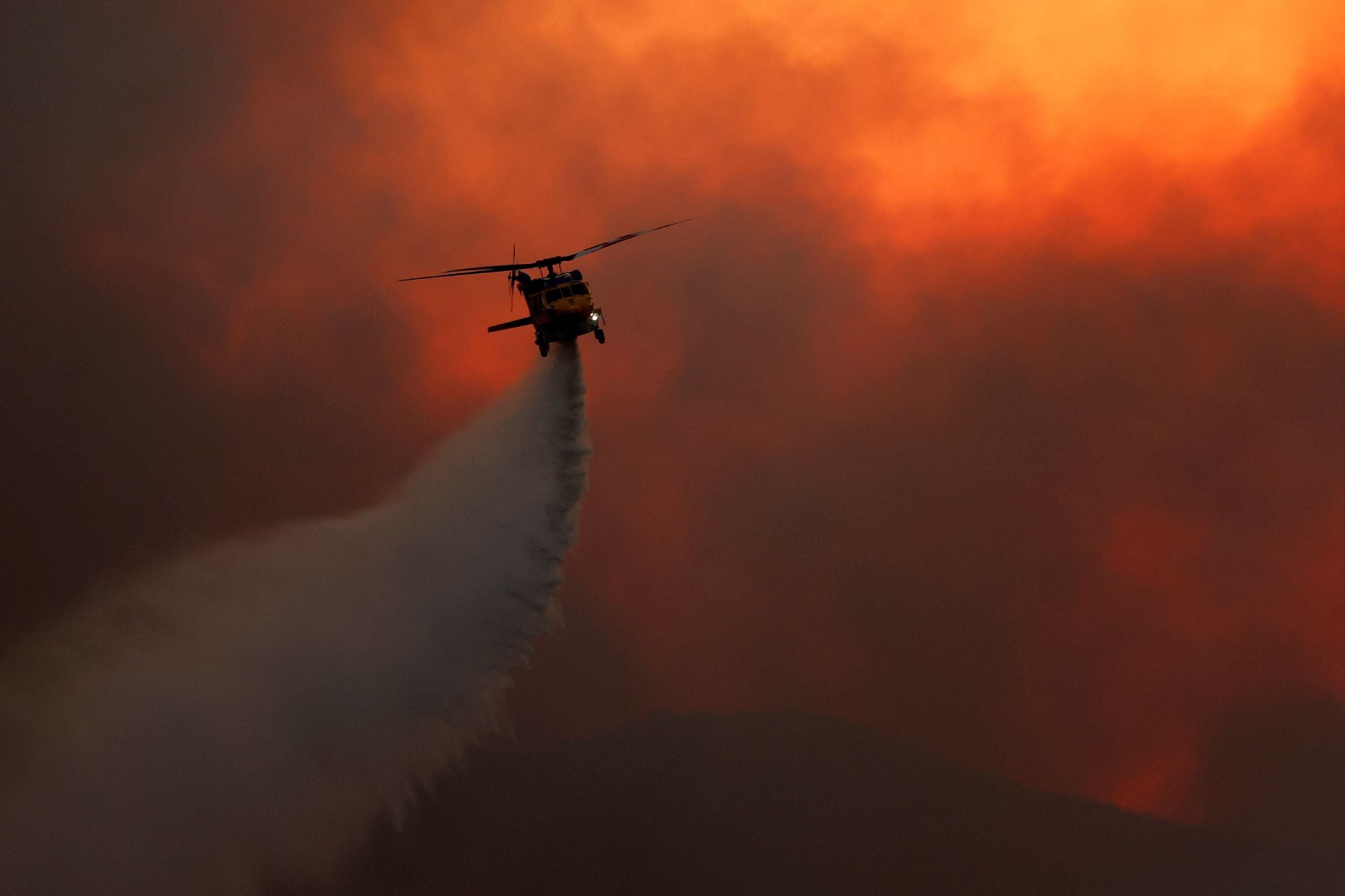 A firefighting helicopter drops water on the Bryson Fire on October 15, 2026, in Malibu, California. 